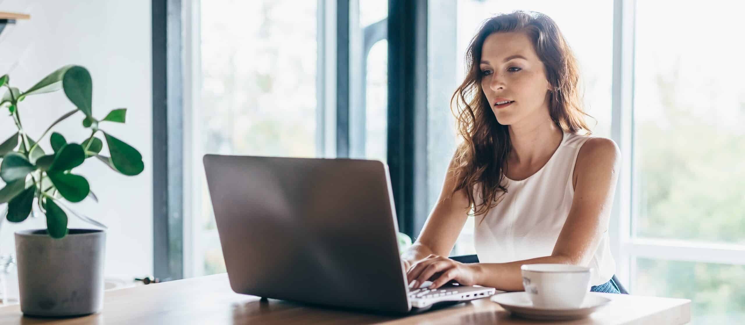 women sitting at a counter using her laptop